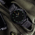 Luminox Pacific Diver Herenhorloge 44mm met zwarte kast en rubberen band, geplaatst op een groene tactische tas. Zwitsers uurwerk met lichtgevende wijzers.