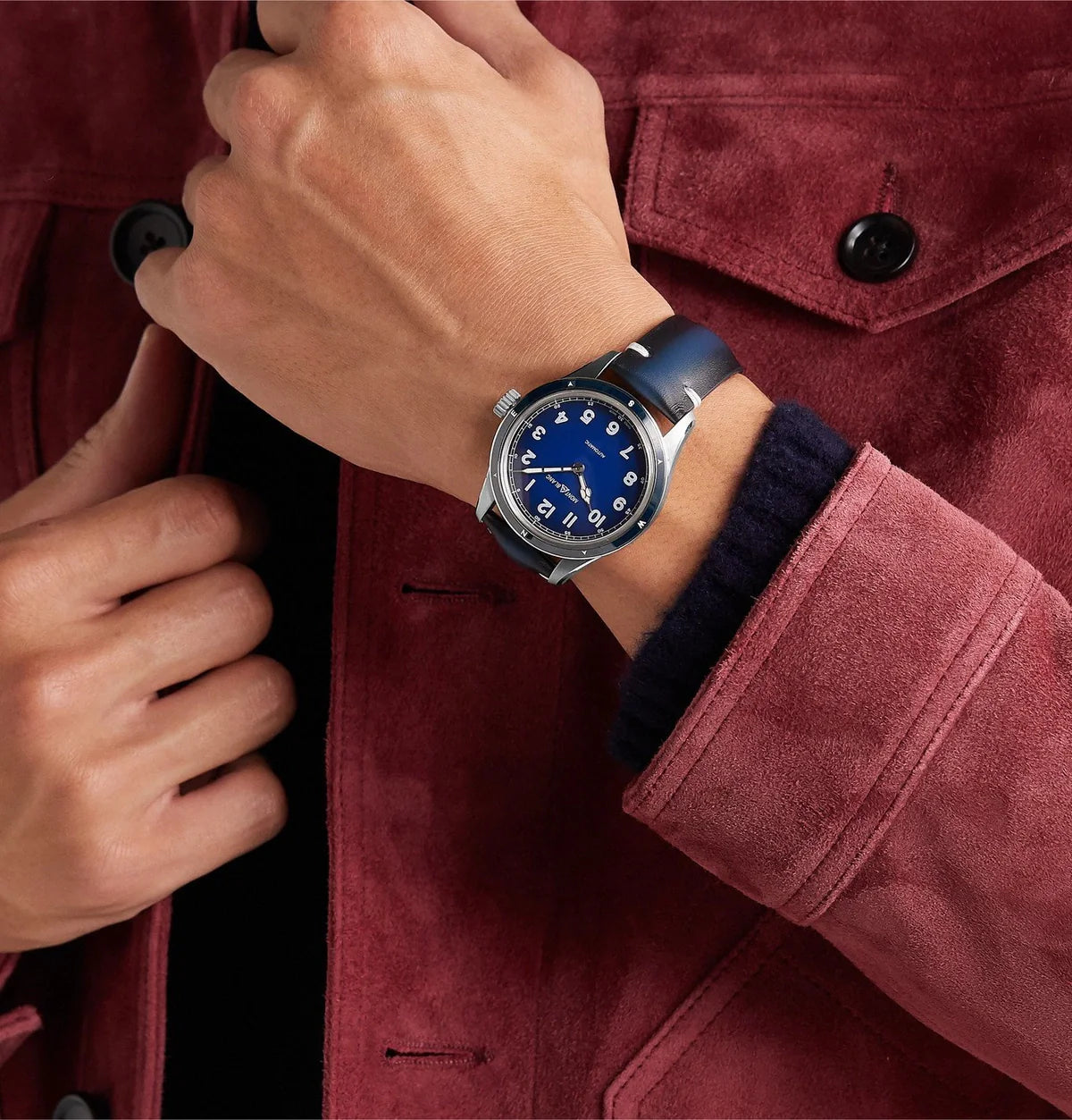 Montblanc 1858 Automatic 126758 Herenhorloge 40mm met blauwe wijzerplaat en leren band, gedragen bij een bordeauxrode jas. Luxe Swiss Made horloge voor heren.